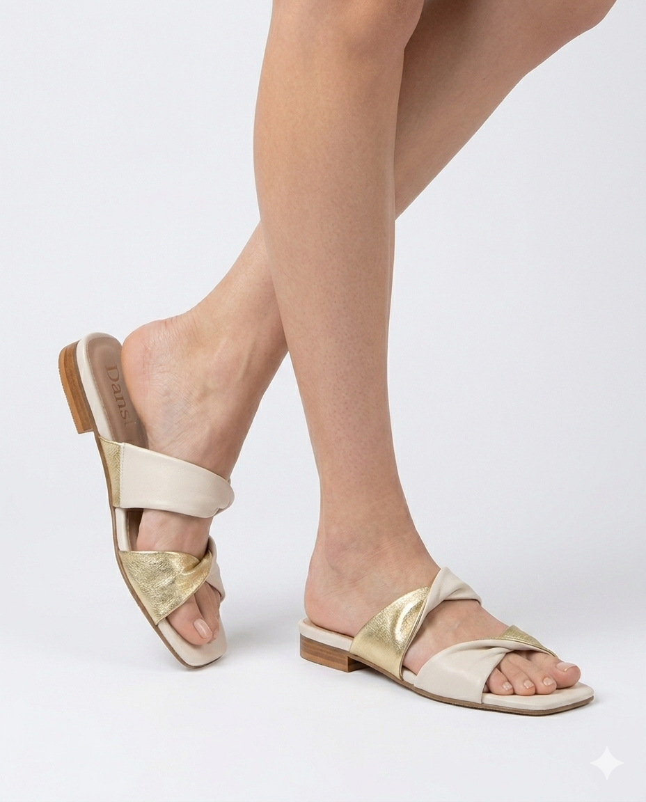 Modelo luciendo sandalias planas destalonadas tipo pala en piel color crema y metalizado oro modelo Nora Dansi
