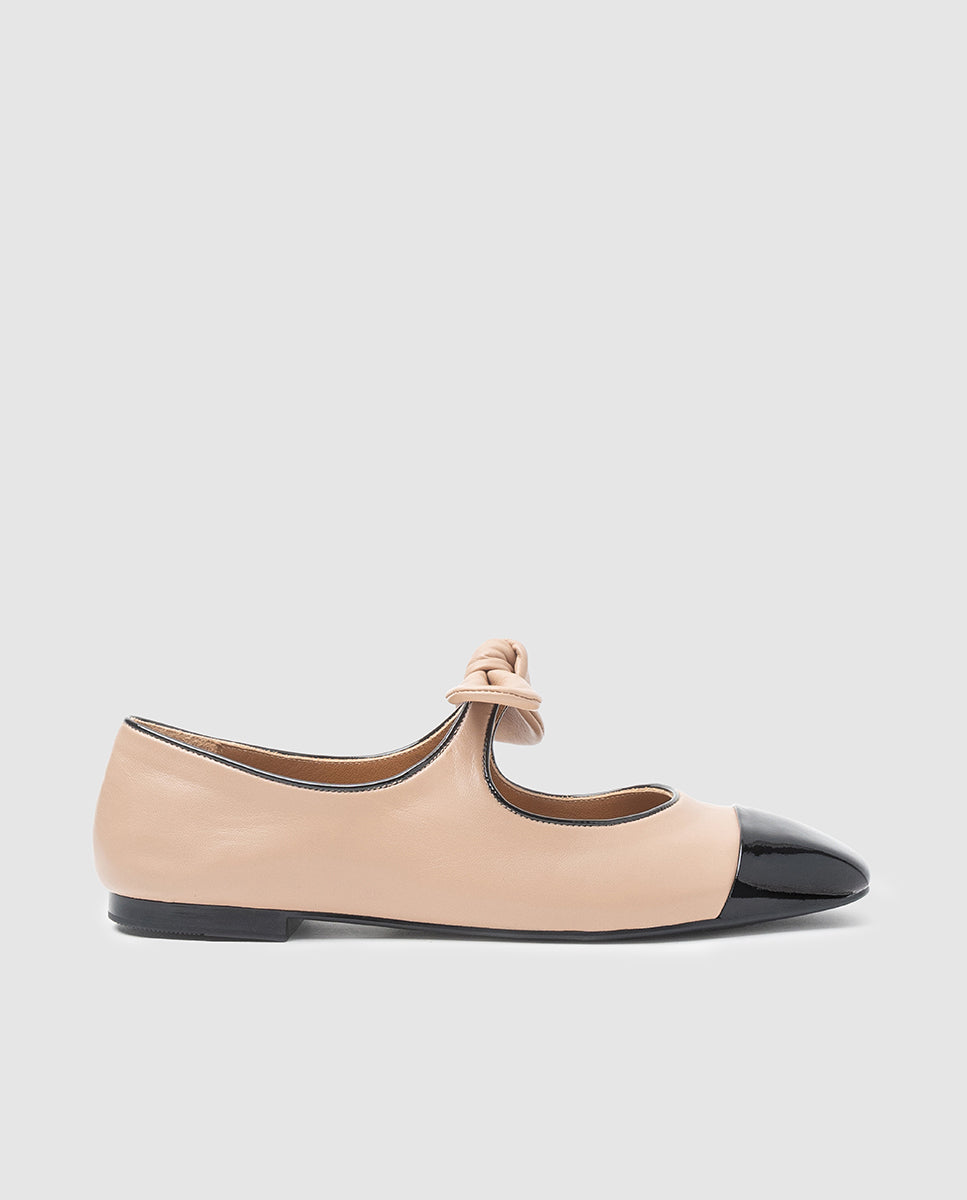 Vista lateral zapato plano tipo merceditas Paula en piel beige con puntera charol negro y lazo