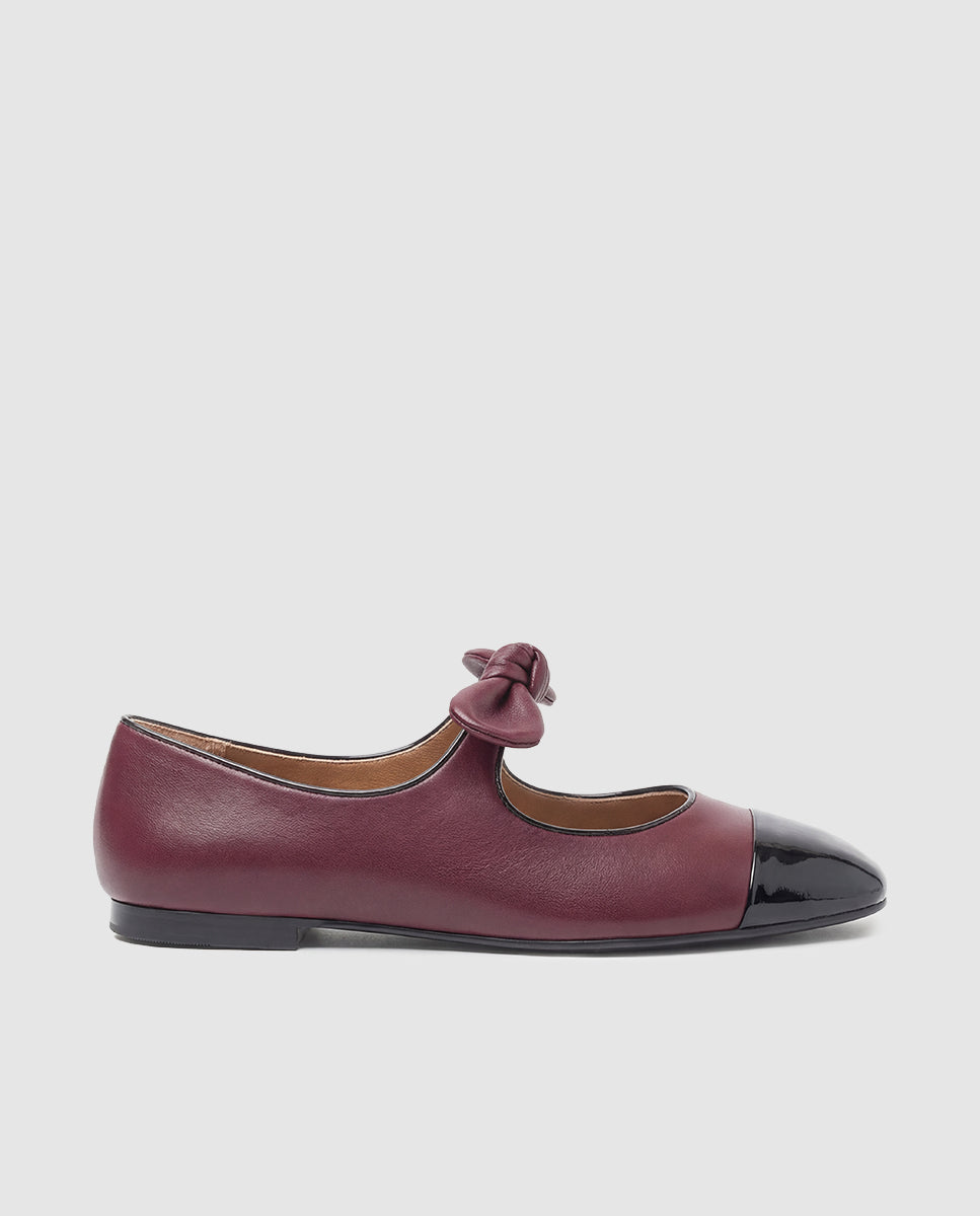 Vista lateral zapato plano tipo merceditas Sofia en piel burdeos con puntera charol negro y lazo