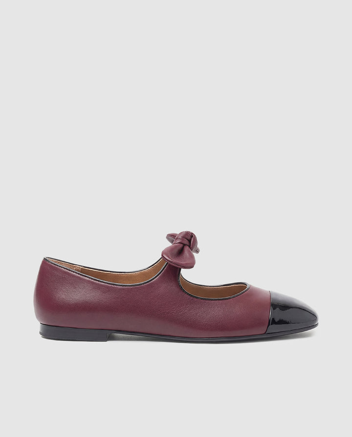 Vista lateral zapato plano tipo merceditas Sofia en piel burdeos con puntera charol negro y lazo