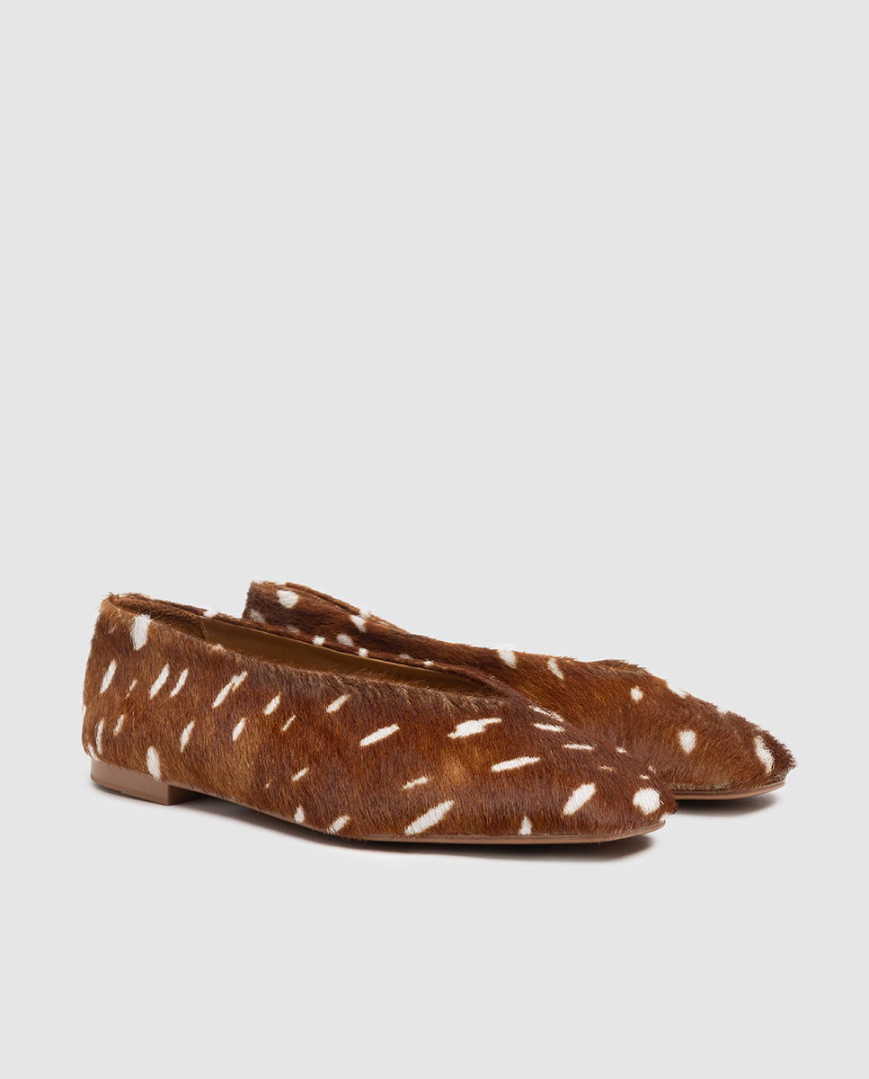 Vista frontal 3/4 de zapatos planos de mujer en piel horsy color cuero con manchas blancas