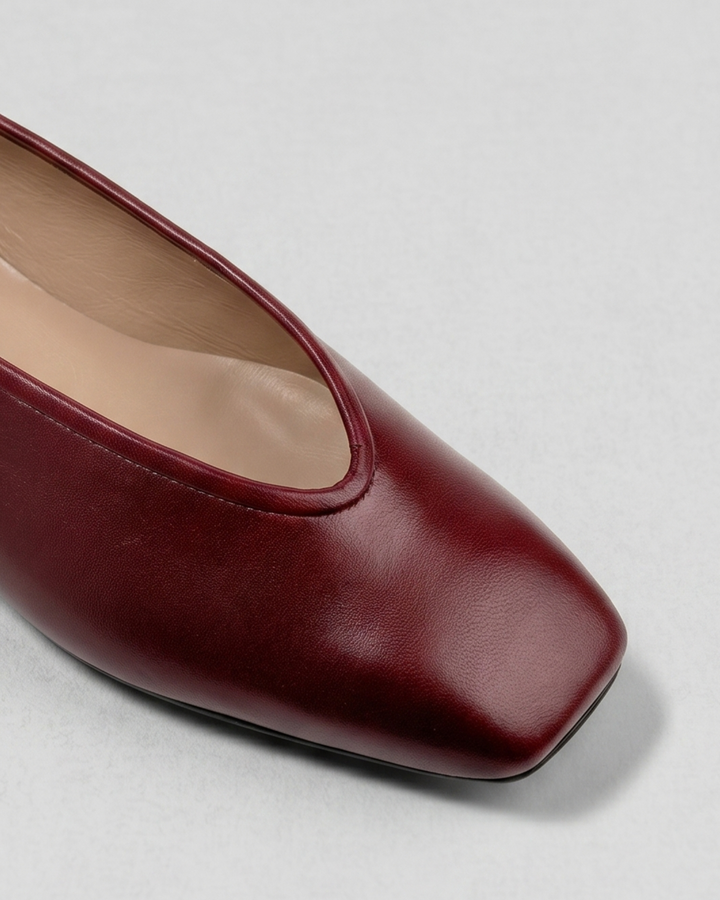 Primer plano del escote en V y punta cuadrada en zapato plano elegante de suave piel color granate Dansi
