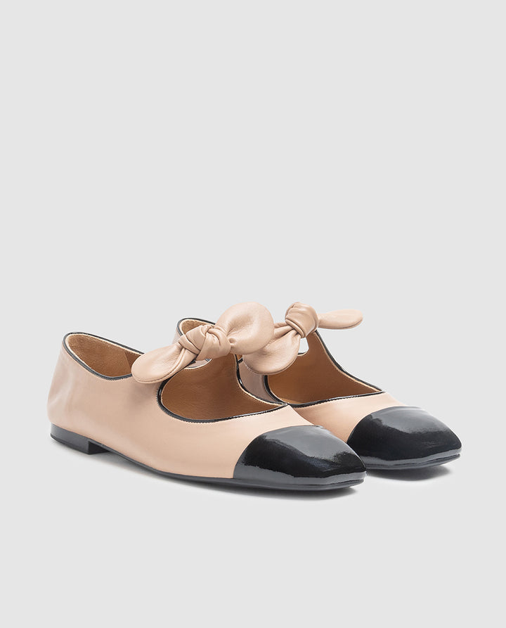 Vista frontal de zapatos tipo merceditas en piel bicolor beige y negro con detalle de lazo en empeine