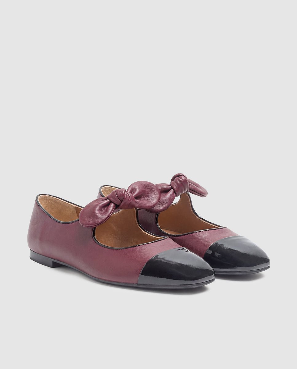 Vista frontal de zapatos tipo merceditas en piel bicolor burdeos y negro con detalle de lazo en empeine