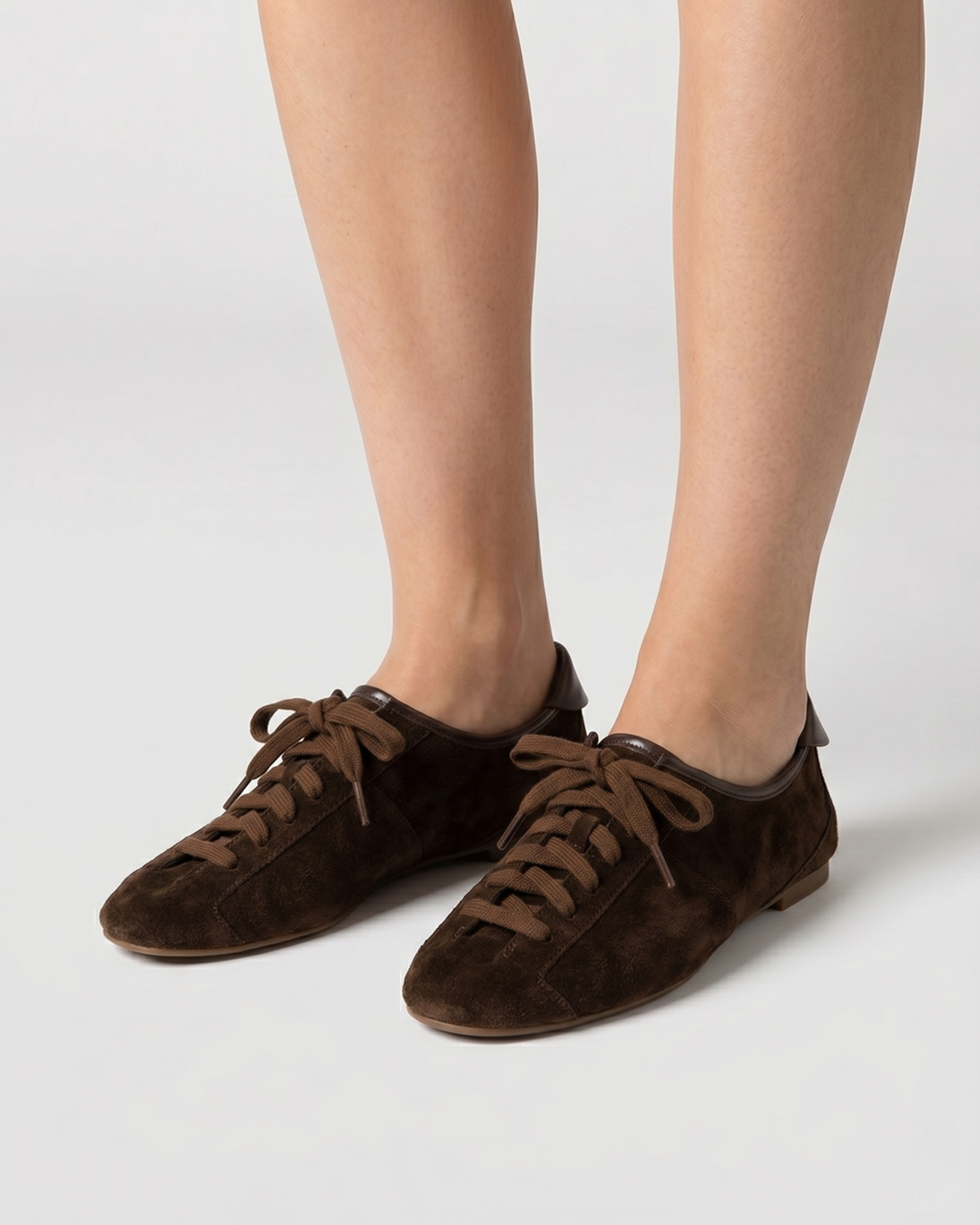 Modelo llevando zapato plano casual tipo zapatilla en ante marrón chocolate con cordones