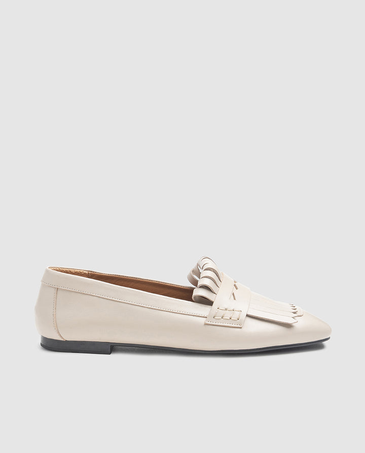 Vista de perfil del zapato plano Noa en piel color sabia con flecos y tacón de 1,5 cm
